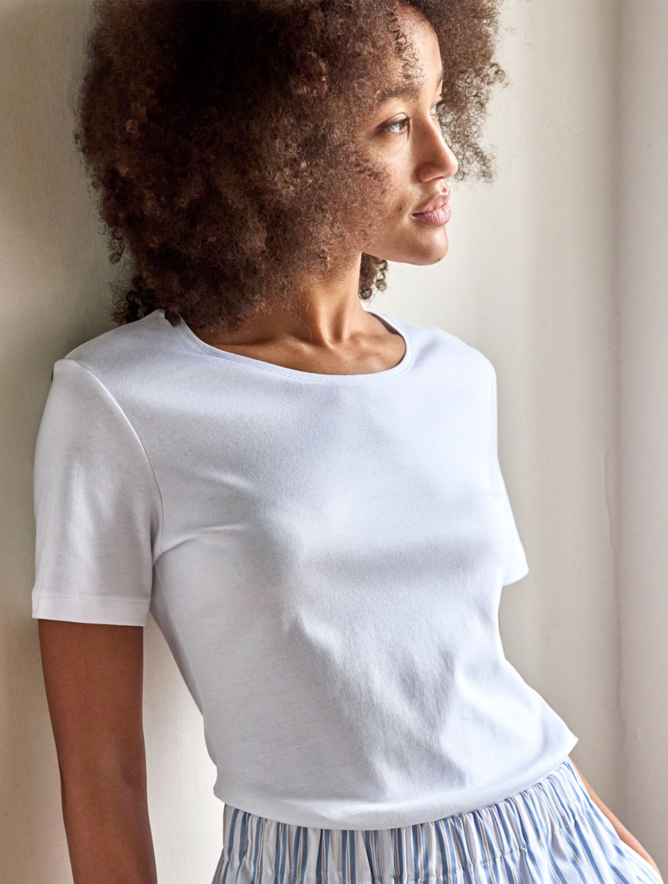 Frau mit Locken trägt weißes T-Shirt