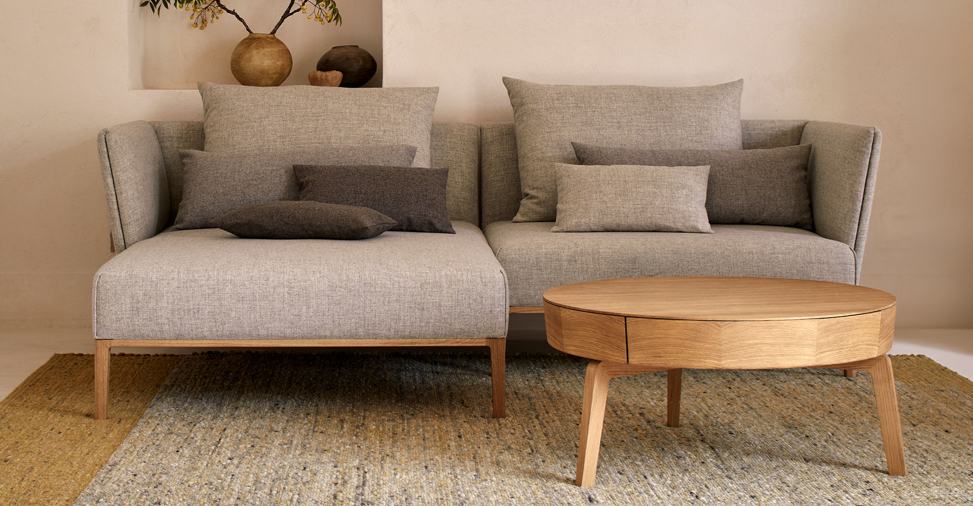 Graues Sofa mit Couchtisch steht vor beiger Wand