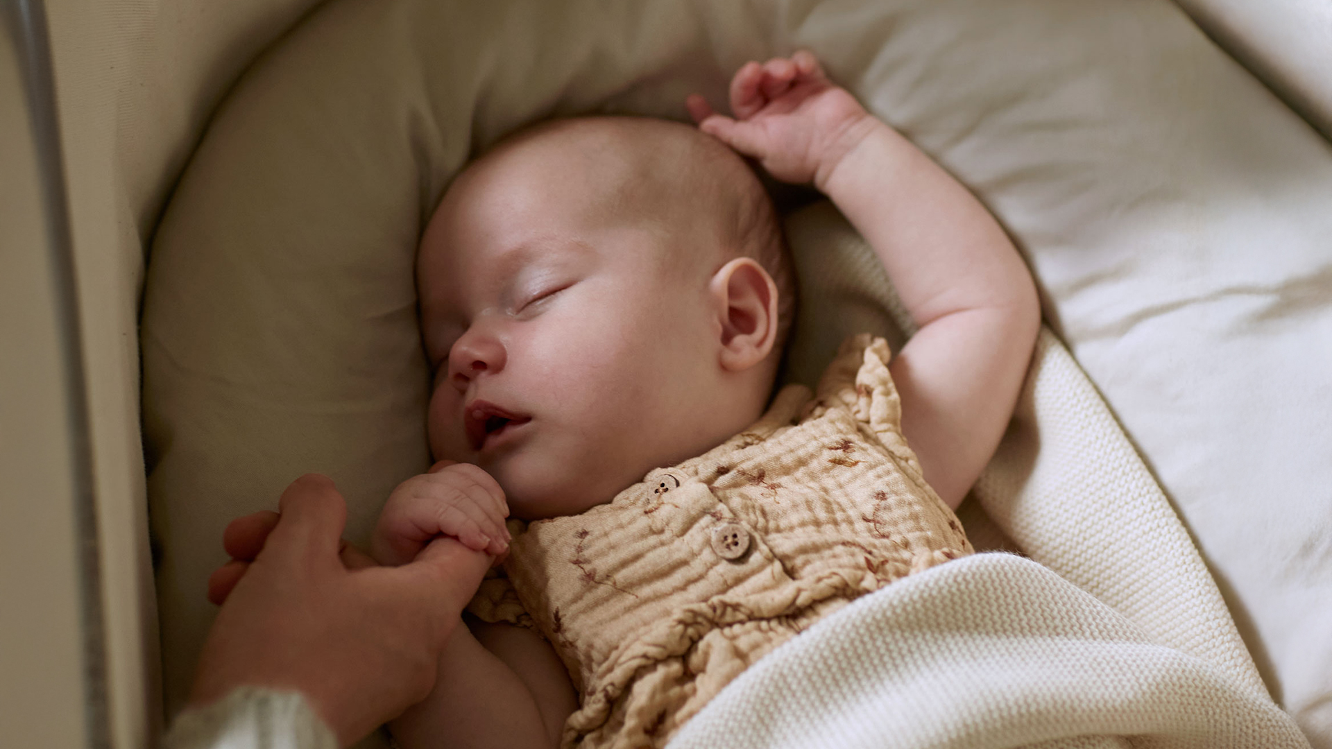 Baby schläft und hält den Finder eines Erwachsenen