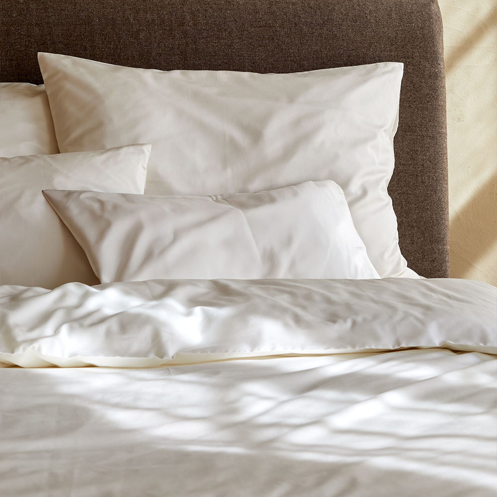 Weiße Bettwäsche auf einem Bett drapiert