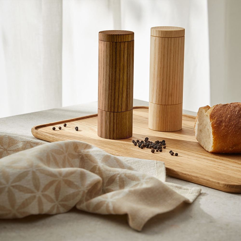 Pfeffermühle und Salzmühle stehen auf einem Tablett aus Holz