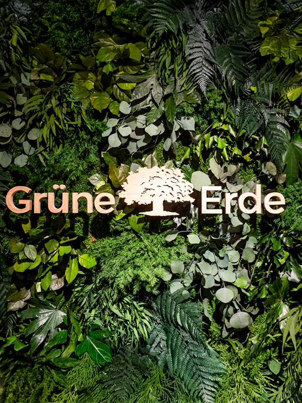 Grüne Pflanzenwand mit Logo und natürlichem Markenauftritt