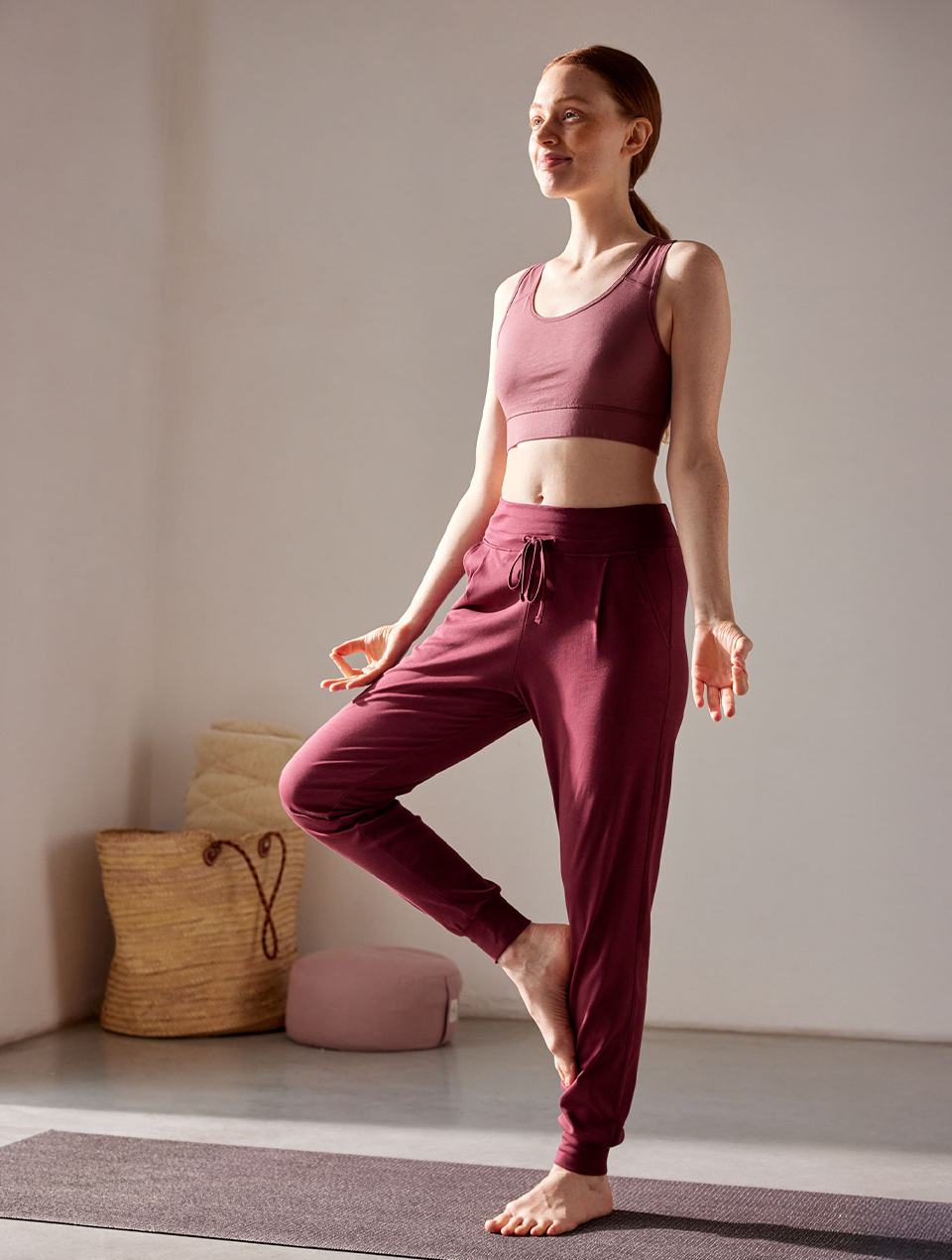 Frau macht Yoga und trägt rote Yogahose und Yogabra